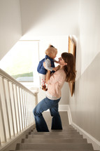 mother holding her toddler daughter standing in a stairway