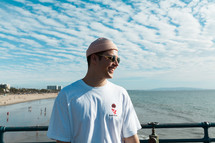 a man in a beanie standing on a beach 