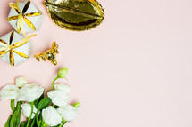 white flowers, gold dish, and gifts on a pink background 