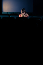 woman sitting in a dark empty church with her head bowed in prayer