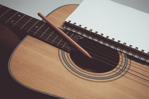 pencil and journal on a guitar 