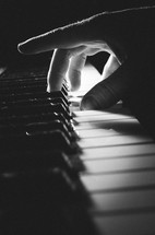 A b&w shot of a man's hand playing a chord on the keyboard