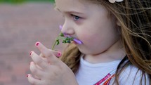 a little girl smelling a flower 