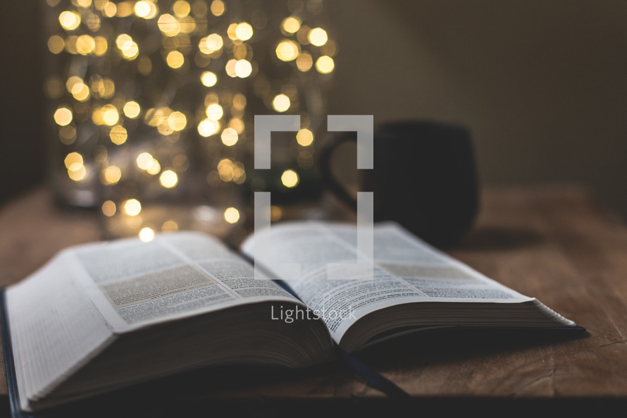 open Bible on a coffee table in front of bokeh lights from a Christmas tree 
