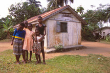 children standing in front of a hut 