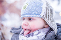 a boy child playing outdoors in snow and catching snowflakes on his tongue 