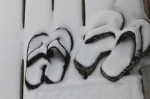 flip flops on a deck covered in snow 