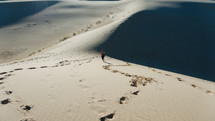 a man walking across sand dunes in a desert 