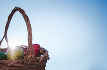 Colored easter eggs in a wicker basket with the sun's rays