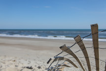 Broken reed fenceon beach at ocean.