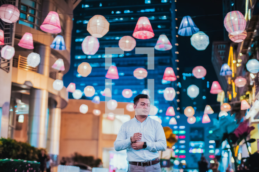 a man standing outdoors under paper lanterns 
