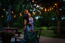 a couple standing on a backyard deck in summer 
