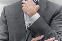 a man in a suit fixing his bow tie 