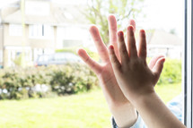 Boy holding his hand against glass mirroring his fathers hand