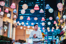 a man standing outdoors under paper lanterns 