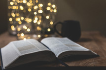 open Bible on a coffee table in front of bokeh lights from a Christmas tree 
