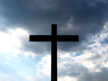 Christian cross silhouette over a cloudy sky background