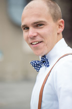 a man in suspenders and a bow tie 