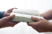a couple holding an open Bible together - share the good news