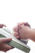 woman holding a Bible and a man with praying hands held over it