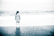 woman standing in water on beach in a dress 