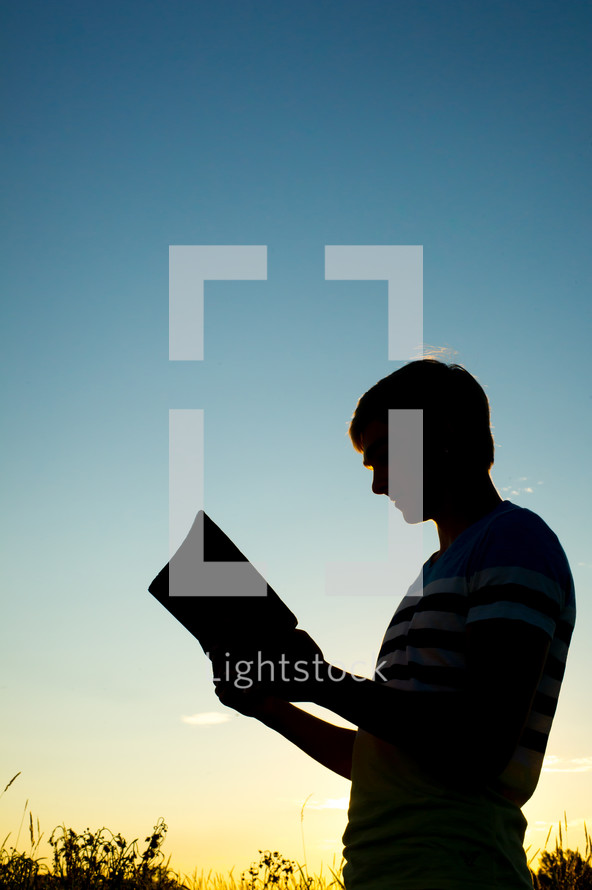 silhouette of a man reading a Bible 