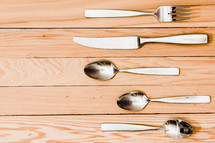 fork, knife, spoons, on a wood floor 