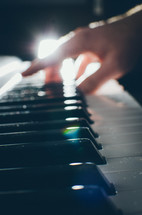 A backlit shot of a man playing a chord on the keyboard