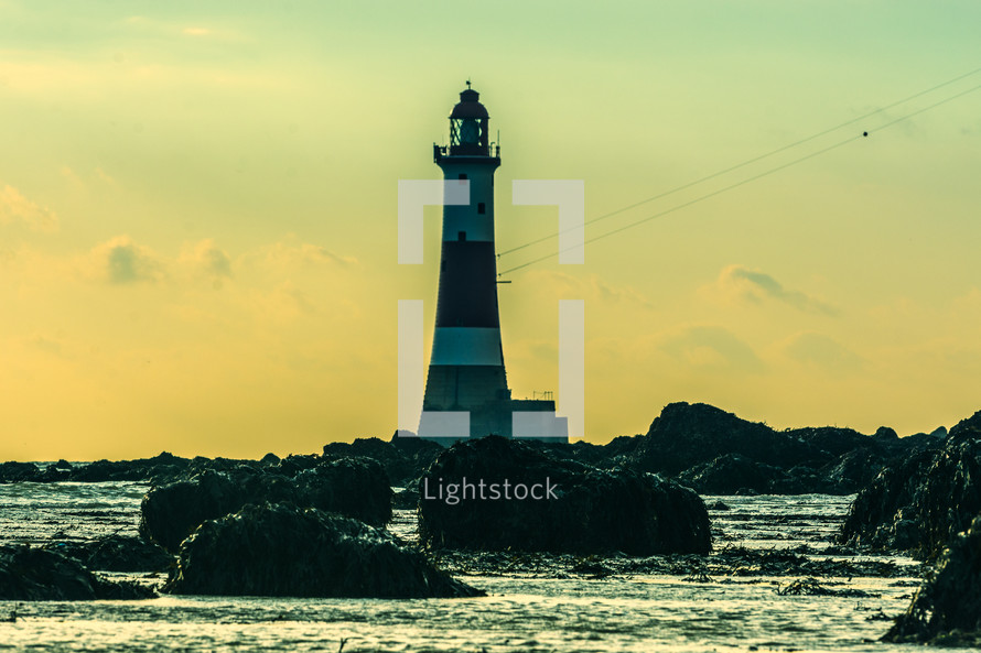 A lighthouse surrounded by water and boulders.