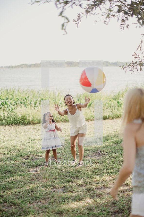 Three people playing catch with a beach ball.