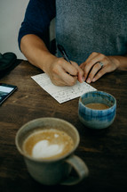 man writing a letter and a cup of coffee with heart shape creamer 