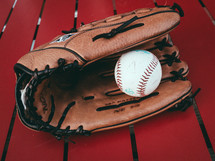 A baseball and glove on top of a red table
