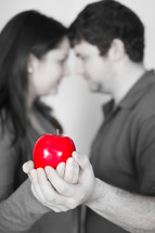 man and woman holding the forbidden fruit (red apple)