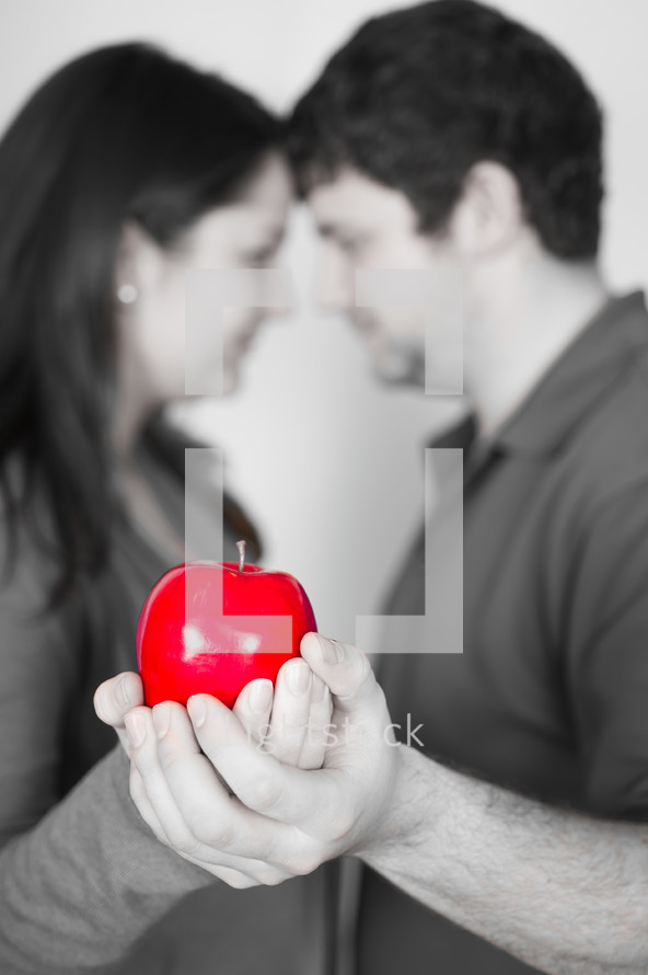 man and woman holding the forbidden fruit (red apple)