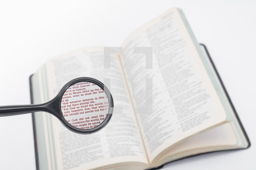 A magnifying glass over a Bible, magnifying John 3:16.