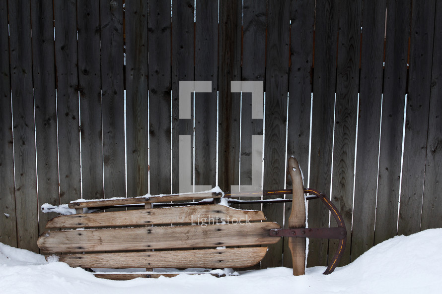 a sled against a wooden fence 