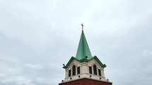 Circling a church steeple on a cloudy overcast day.