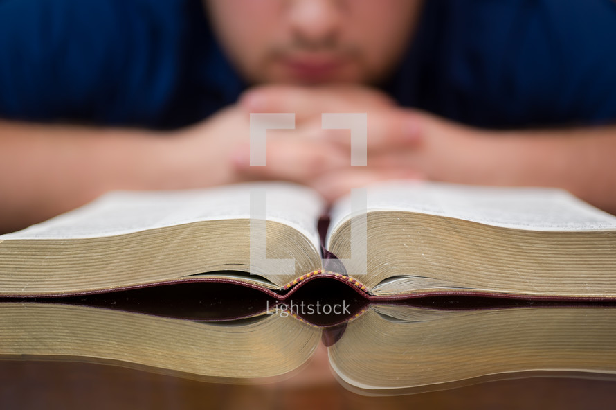 man in prayer in front of a Bible at a Bible study 
