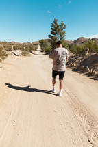 a man walking down a dirt road 
