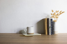 Study concept with coffee cups, books and flowers on brown wooden table. 
