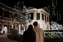 a couple looking at beautiful Christmas lights at night 