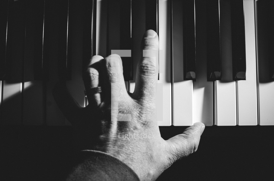 A man's hand plays a chord on a keyboard