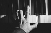 A man's hand plays a chord on a keyboard