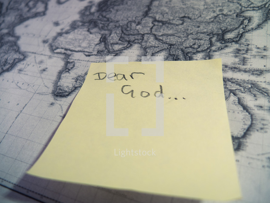 A post-it sticky note with 'Dear God' stuck to a an antique style map.