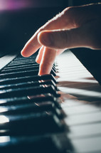 A man's hand playing a note on a keyboard