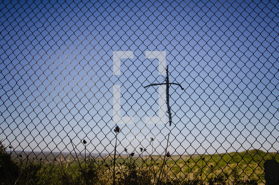 Cross of sticks in a chain link fence.