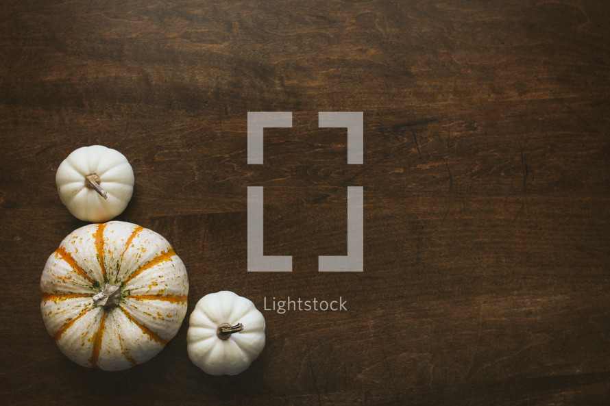 three pumpkins in a corner on a wood table