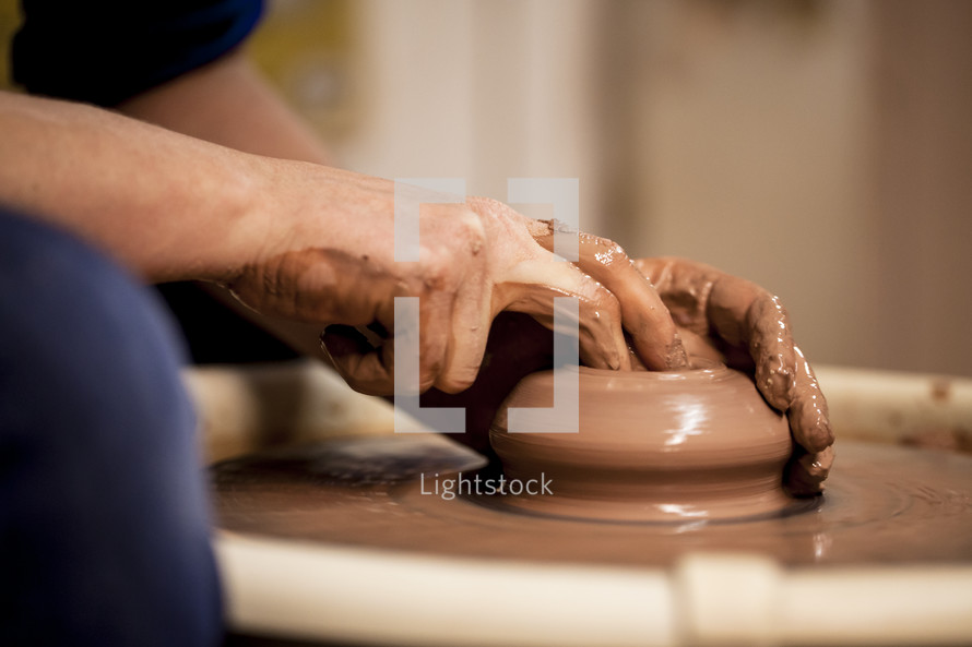 hands on clay on a potter's wheel 