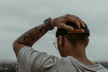 Man with tattoo putting hand on head