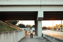 a young man standing under an overpass 